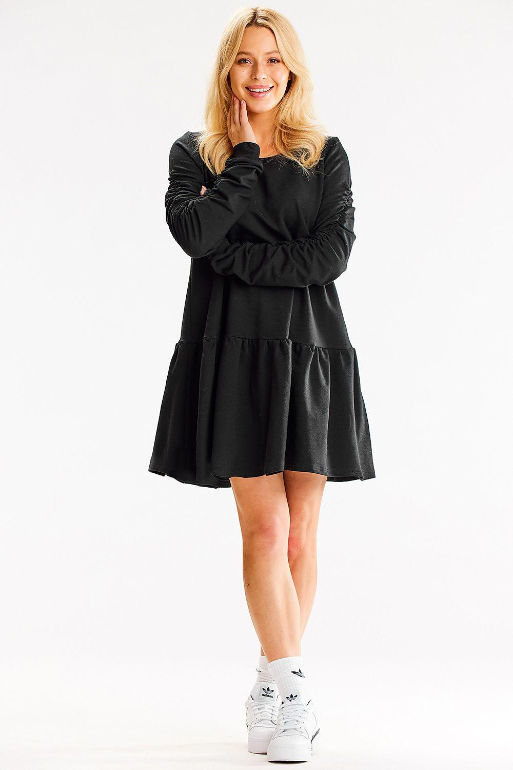 Black long-sleeve daydress with round neck and gathered tiered hem, standing