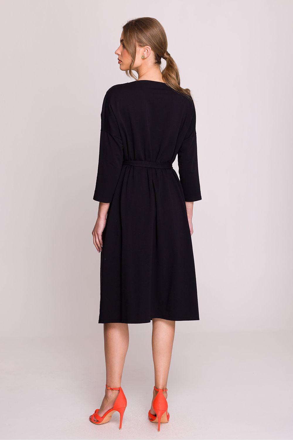 Black daydress from the back with waist tie, three-quarter sleeves, and knee length.