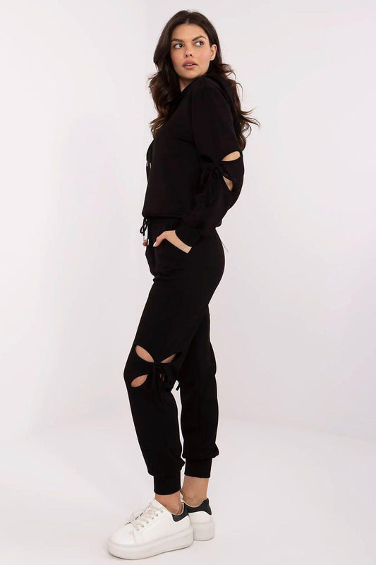 Black tracksuit set, cropped profile view; drawstring hoodie and jogger pants with slits.