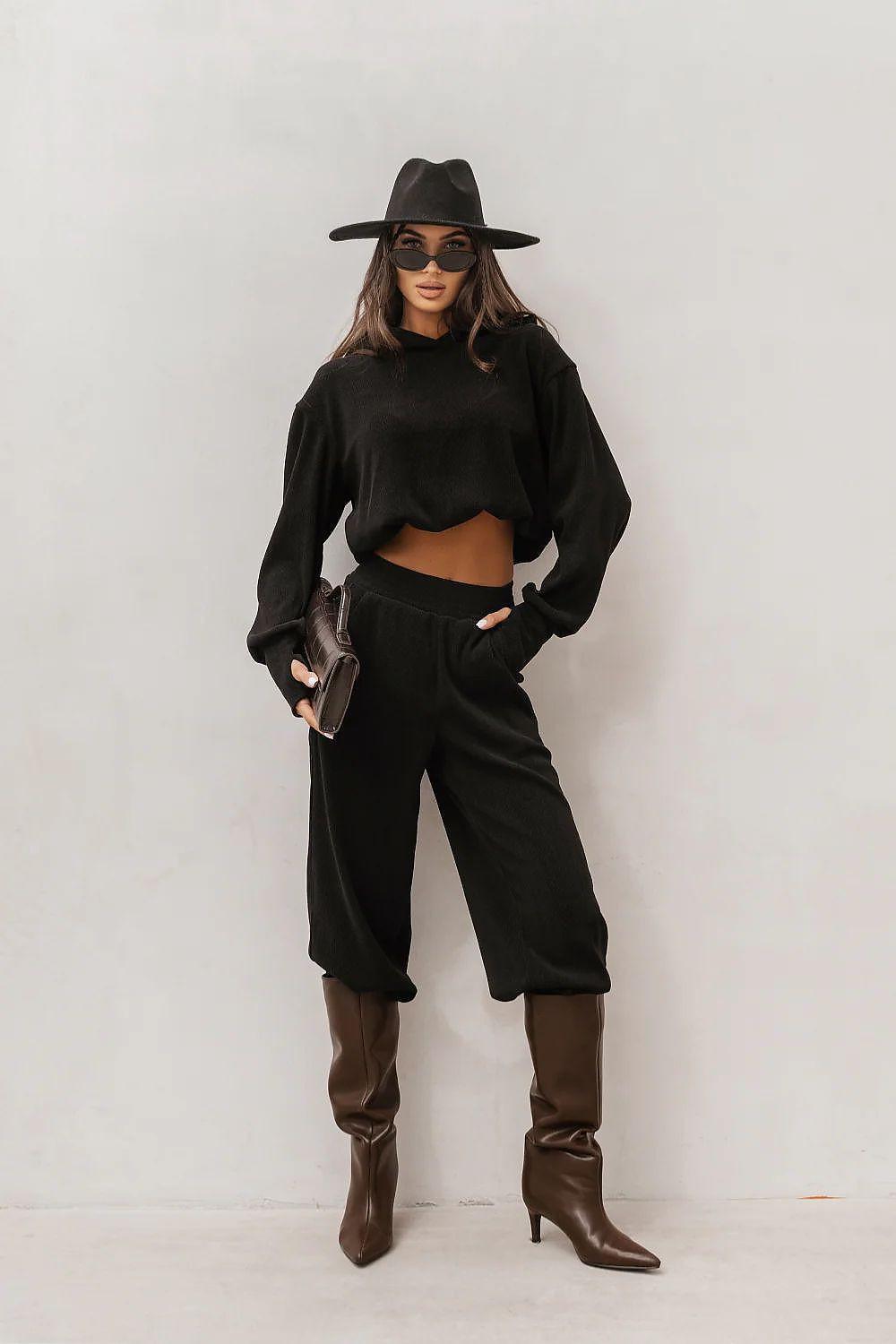 Black sweatshirt and matching sweatpants set with wide-leg cut, worn with hat