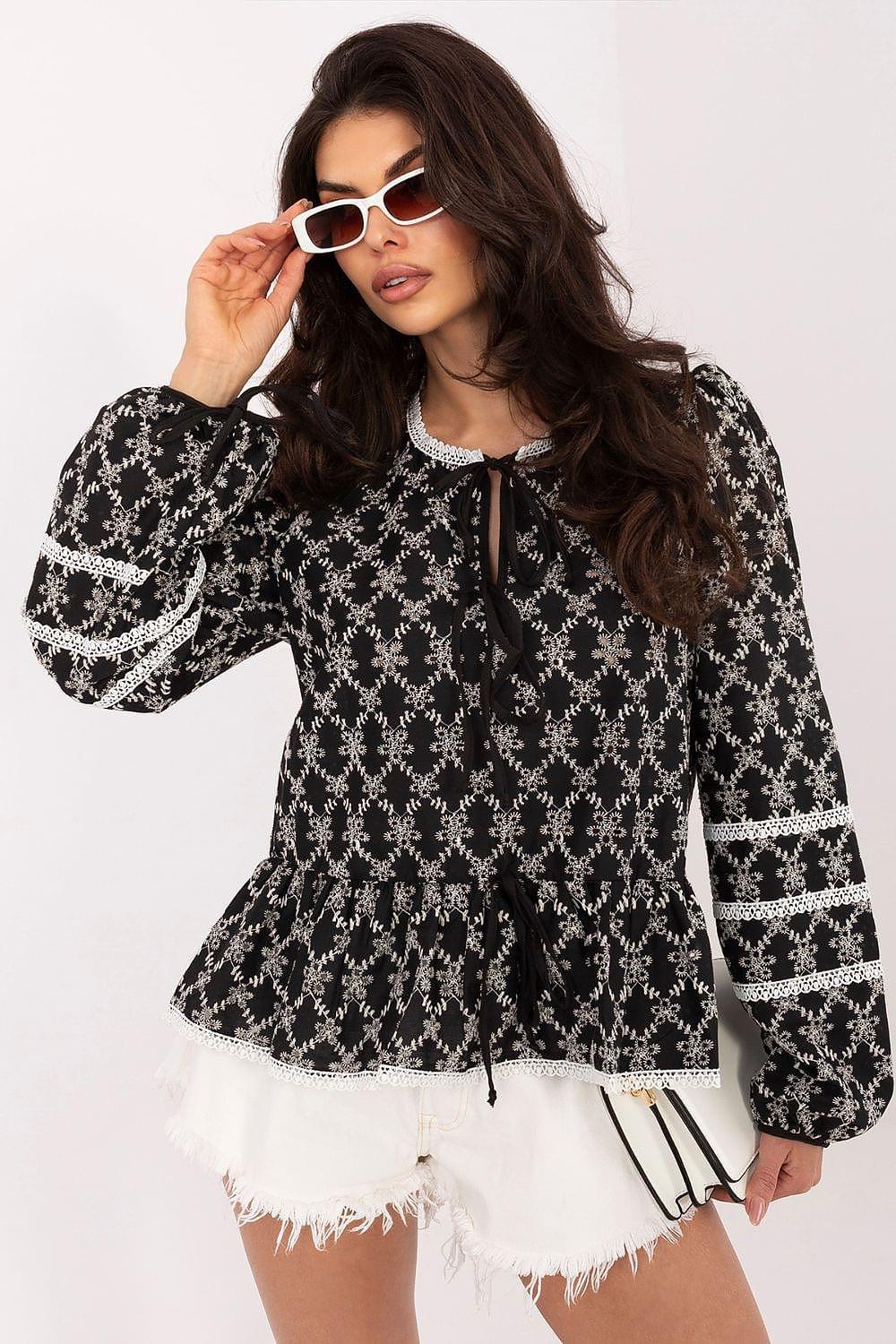 Black patterned peplum blouse with long sleeves, round neck, and white trim