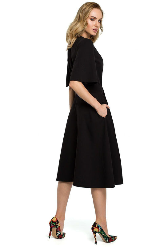 Black short-sleeve daydress, side view; waist tie belt and flared midi skirt