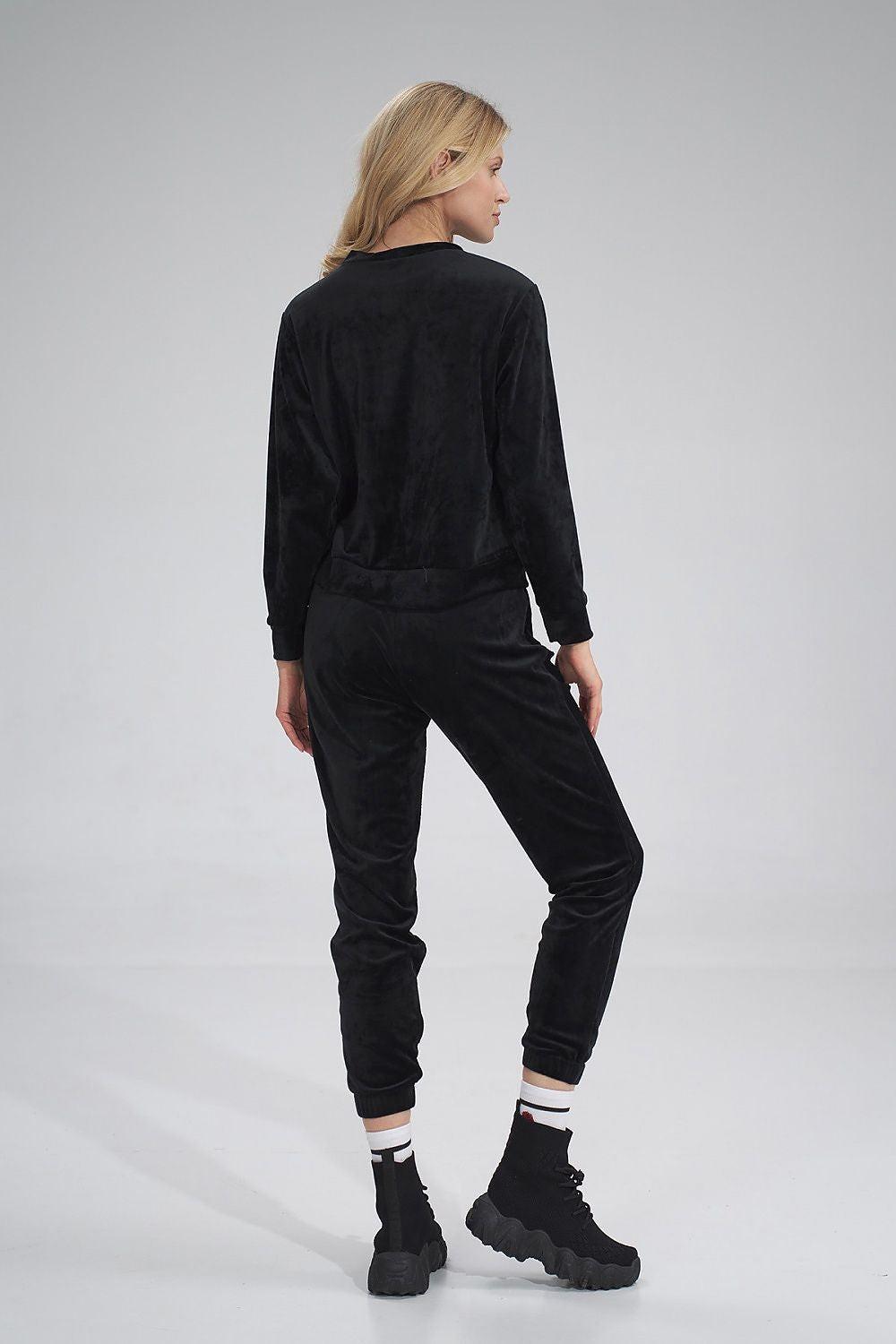 Black tracksuit trousers, back view, elastic waistband and ankle cuffs, tapered jogger fit.