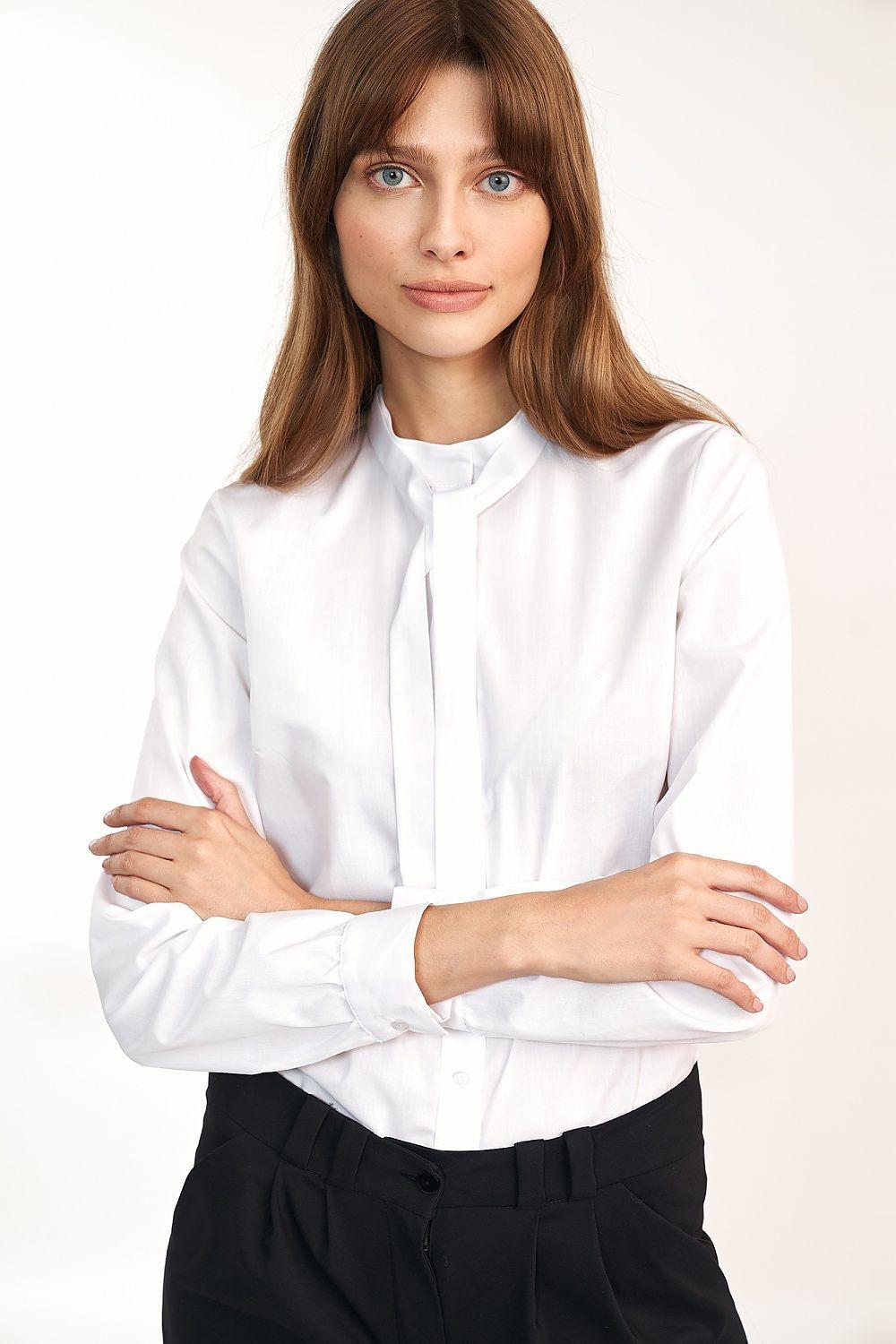 White long-sleeve shirt with bow tie collar and button front, arms crossed
