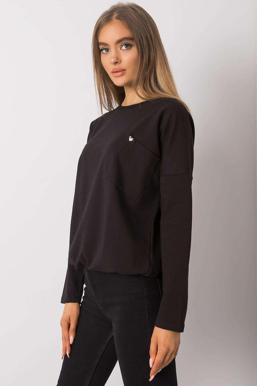 Black blouse with long sleeves and round neck featuring a small chest logo pin, side view