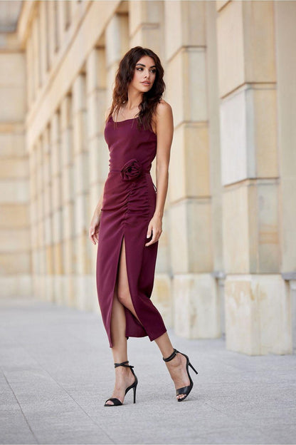 Sleeveless midi cocktail dress with ruched waist and front slit, rose-detail at hip, dark wine.