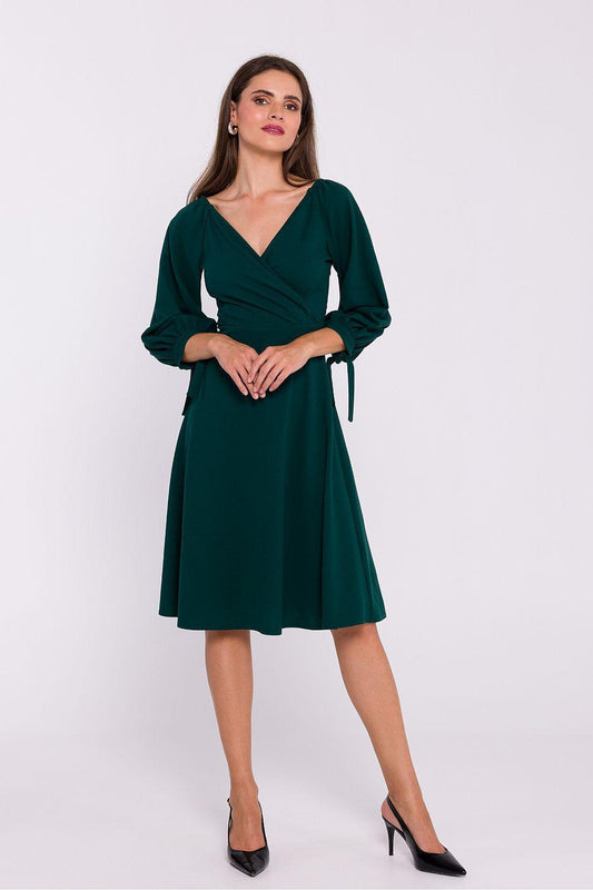 Green V-neck daydress with tie cuffs and ruched waist, long sleeves, knee-length.