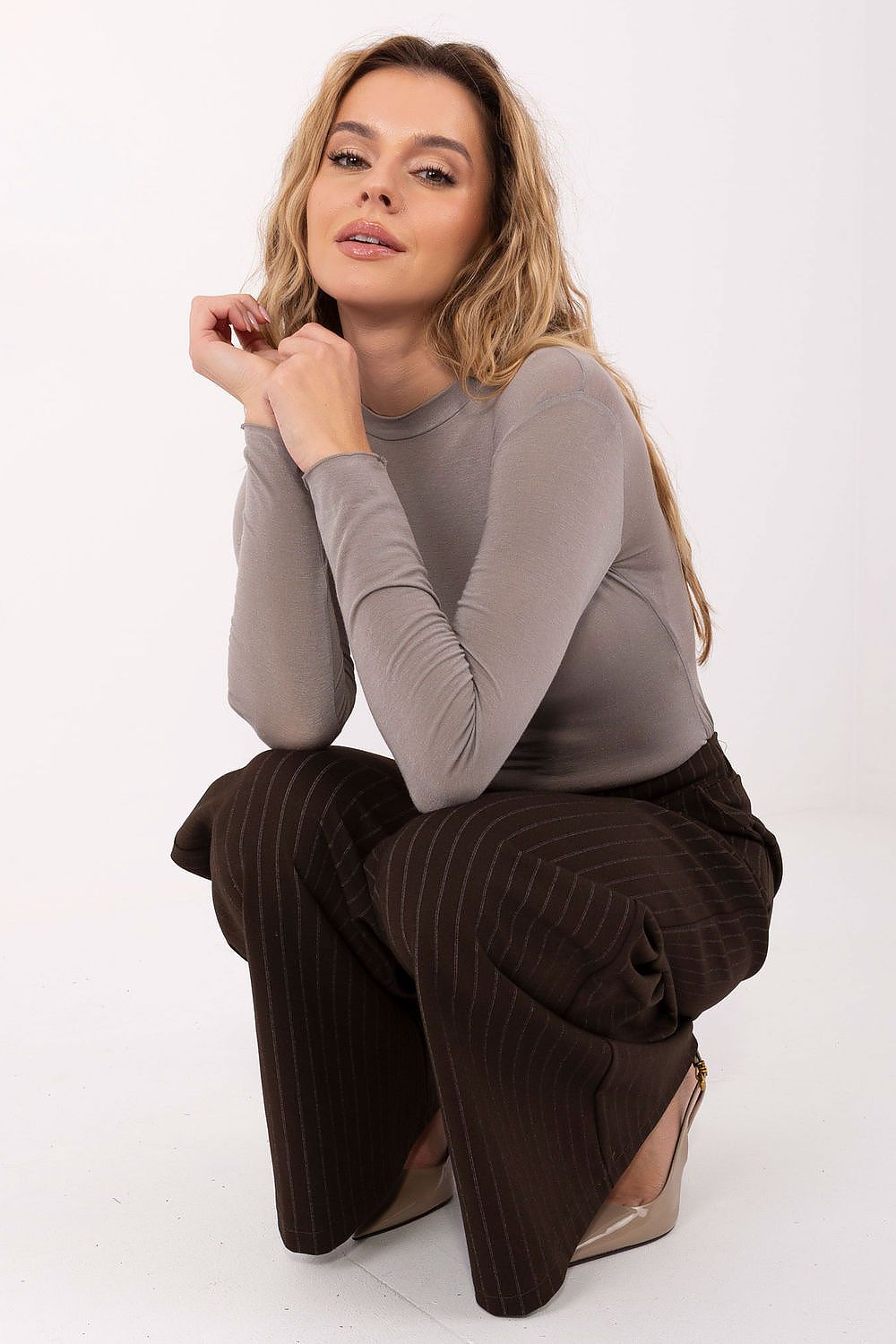 Taupe long-sleeve blouse with crew neck, fitted bodice, and clean hemline