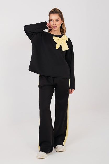 Black two-piece set with long sleeves, yellow bow at neckline, wide-leg pants