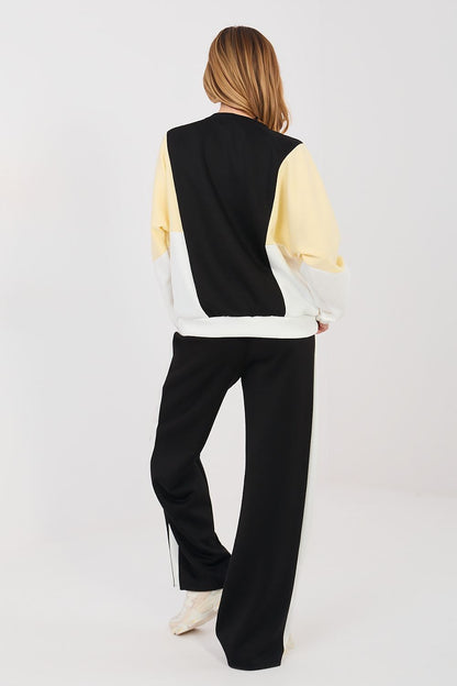 Back view of black sweatshirt and wide-leg black pants with cream sleeves