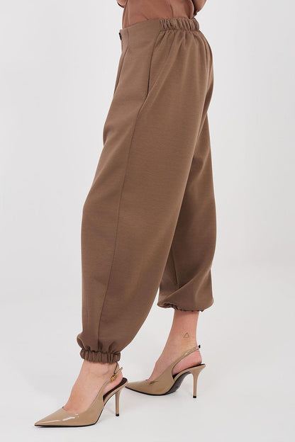 Brown tracksuit trousers with side pockets and elastic ankle cuffs, tapered legs.