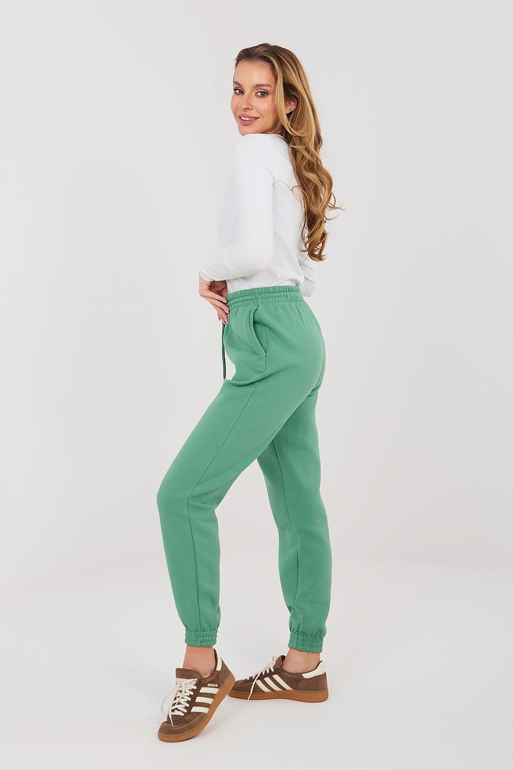 Green tracksuit jogger trousers, side view, tapered legs and ankle cuffs.