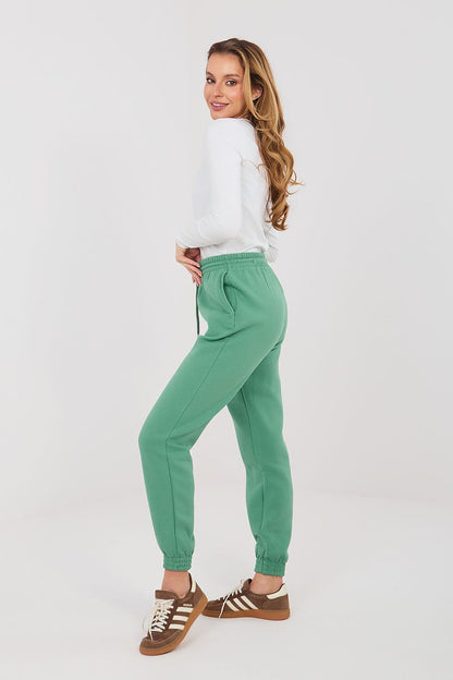Green tracksuit jogger trousers, side view, tapered legs and ankle cuffs.