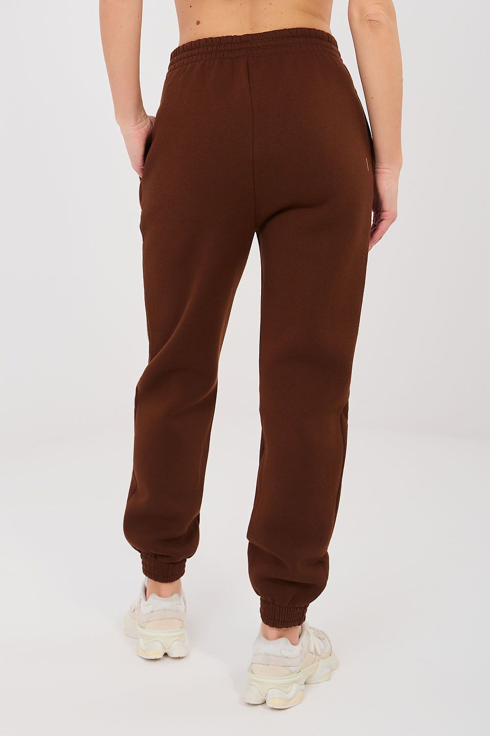 Dark brown sweatpants with elastic waistband and ankle cuffs, close-up.