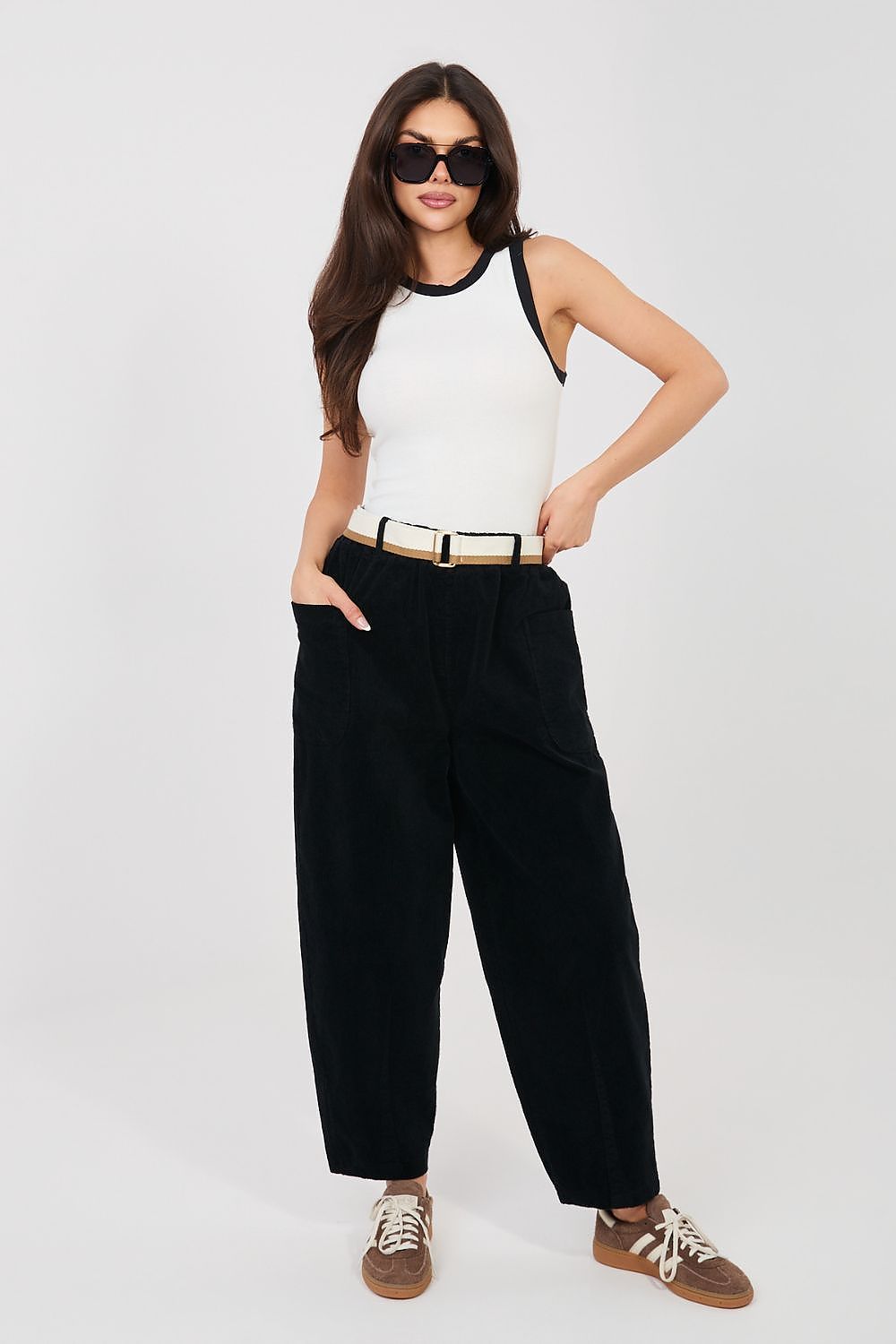 Corduroy trousers in black corduroy, full-body view with belted waist and tapered legs