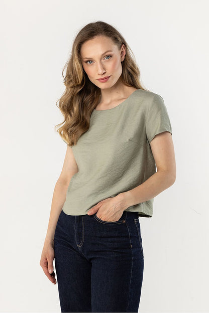 Green short-sleeve crewneck blouse, draped fit, worn with dark jeans