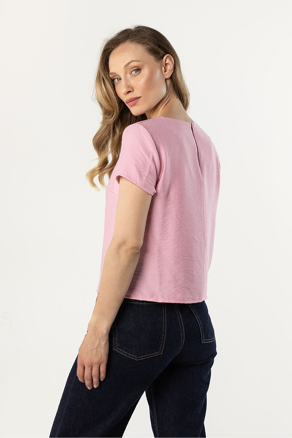 Pink short-sleeve crewneck blouse, back/side view with relaxed drape