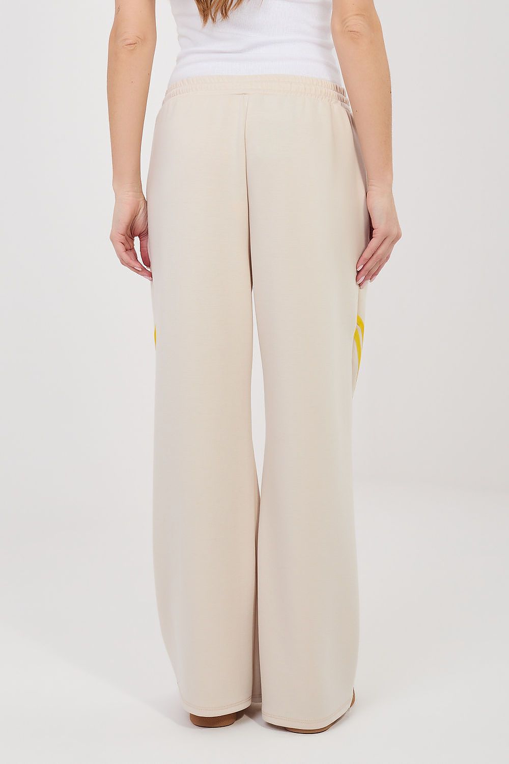 Tracksuit trousers, light beige back view with elastic waist and yellow side stripe detail