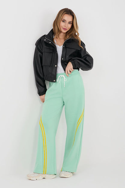 Mint green tracksuit trousers with drawstring waist and yellow side stripe accents.