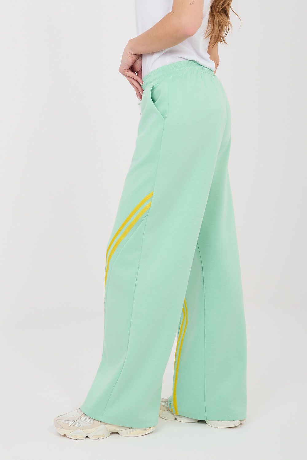 Mint green wide-leg tracksuit trousers with drawstring waist and yellow piping stripe.