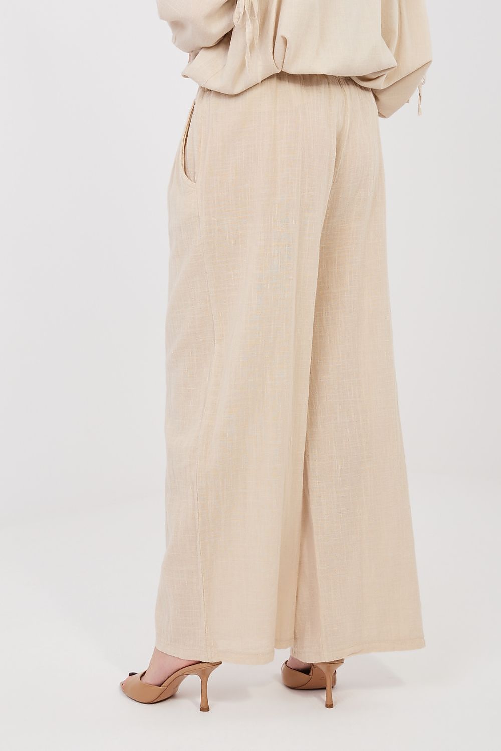 Women’s beige linen-look drawstring wide-leg trousers, close side view of drape