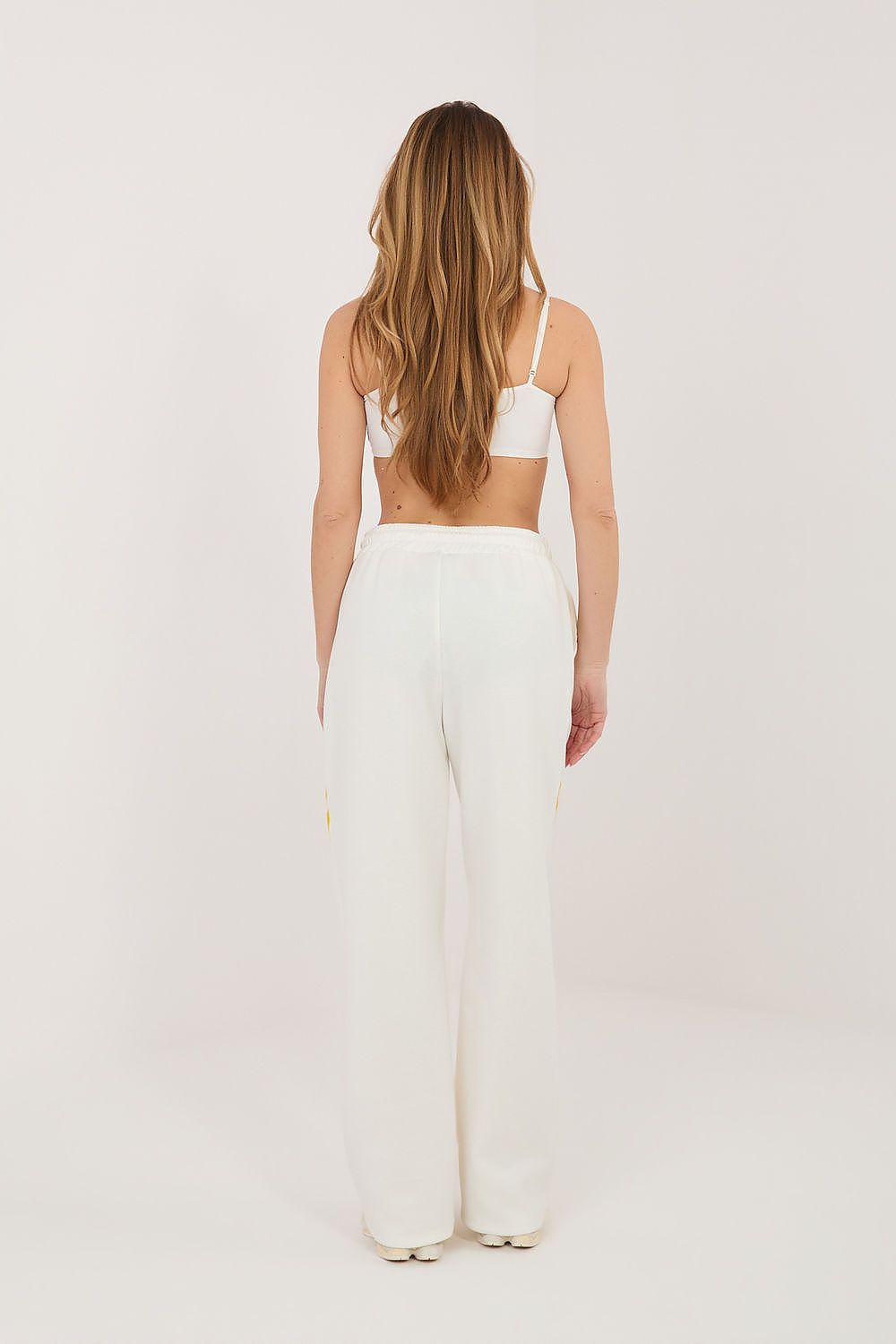 Beige track pants with yellow side piping and relaxed straight-leg fit