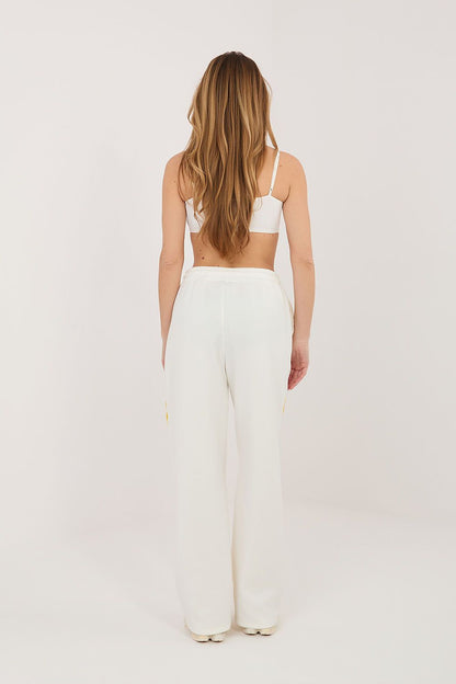 Beige track pants with yellow side piping and relaxed straight-leg fit