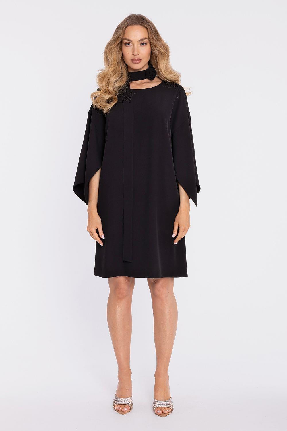 Black cocktail dress with draped sleeves, high neck, and waist belt detail