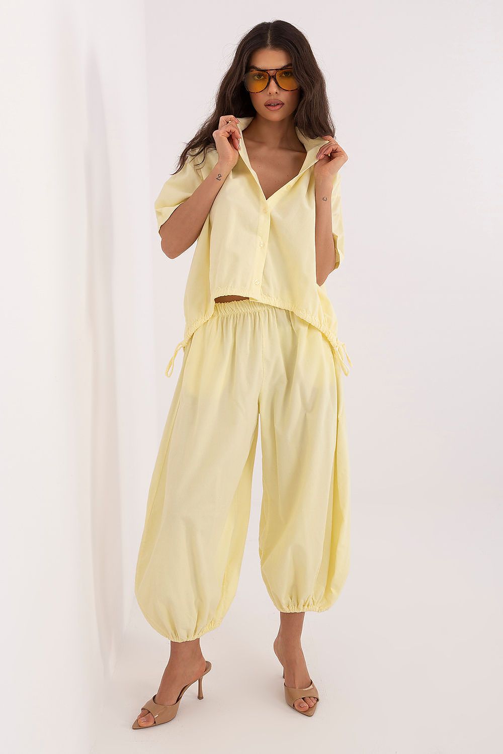 Short-sleeve button-up shirt in pale yellow with collar, open front, and hem ties