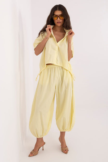 Short-sleeve button-up shirt in pale yellow with collar, open front, and hem ties