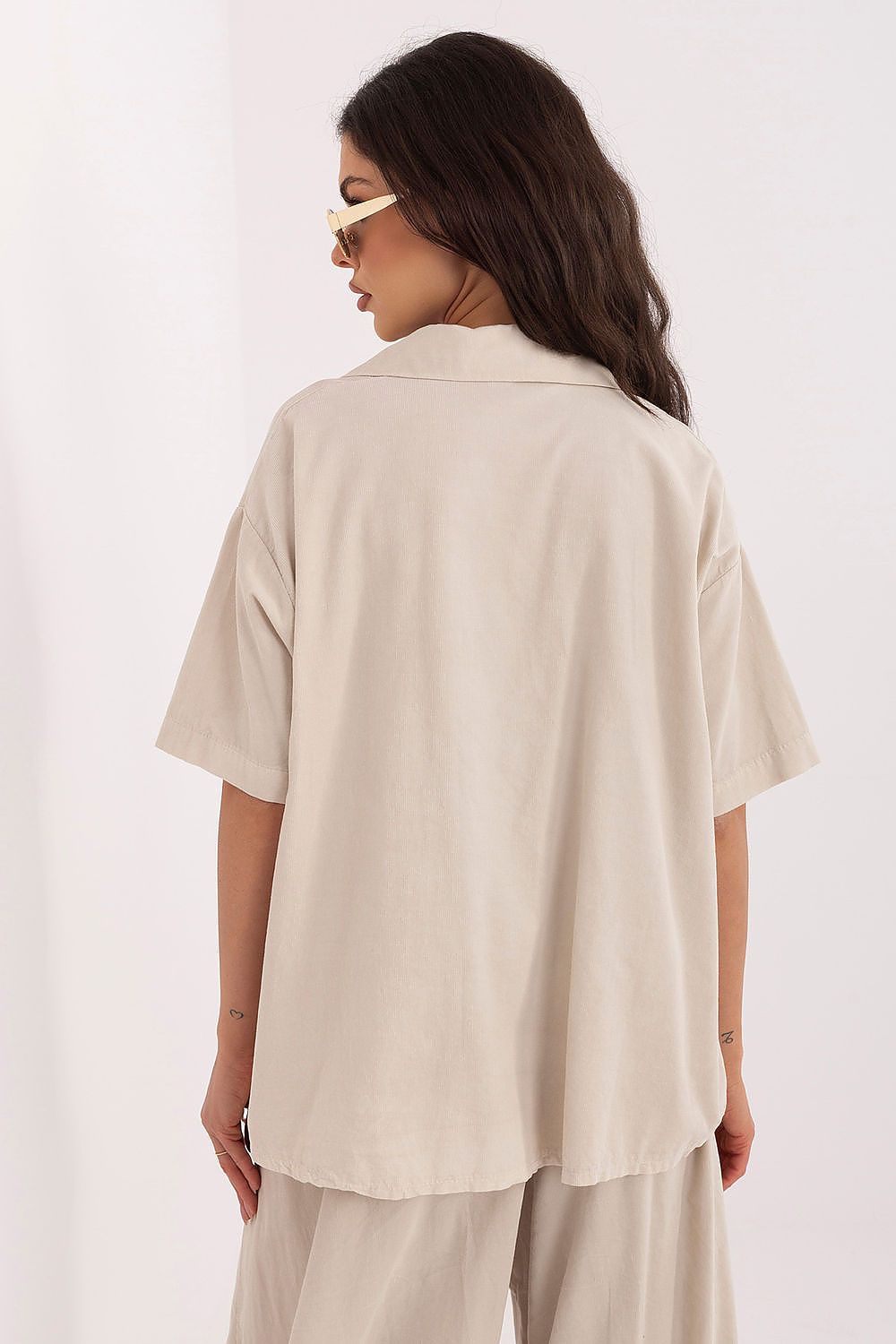 Beige short-sleeve button-up shirt with pointed collar, worn loose