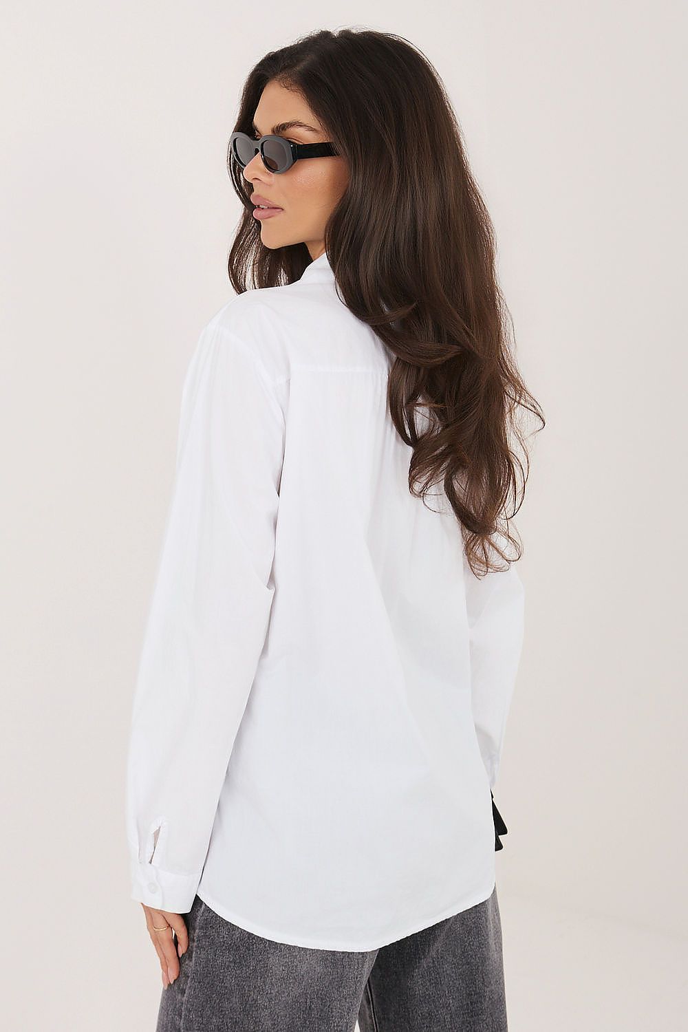 White long-sleeve button-up shirt viewed from the side, with pointed collar