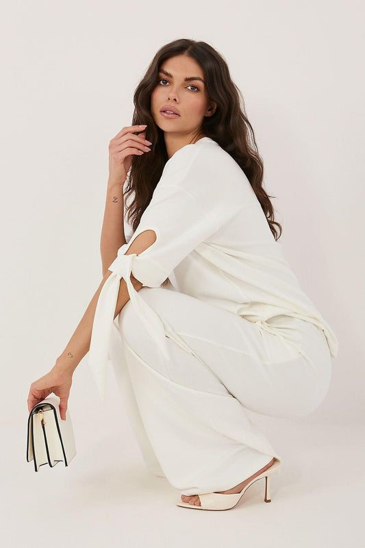White two-piece set with loose top and wide-leg pants, bow ties and bag accessory