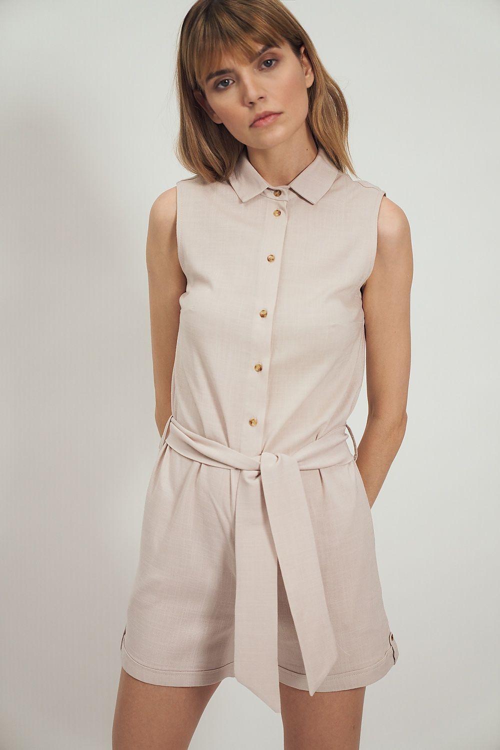 Beige sleeveless button-front romper with waist tie and belted shorts legs