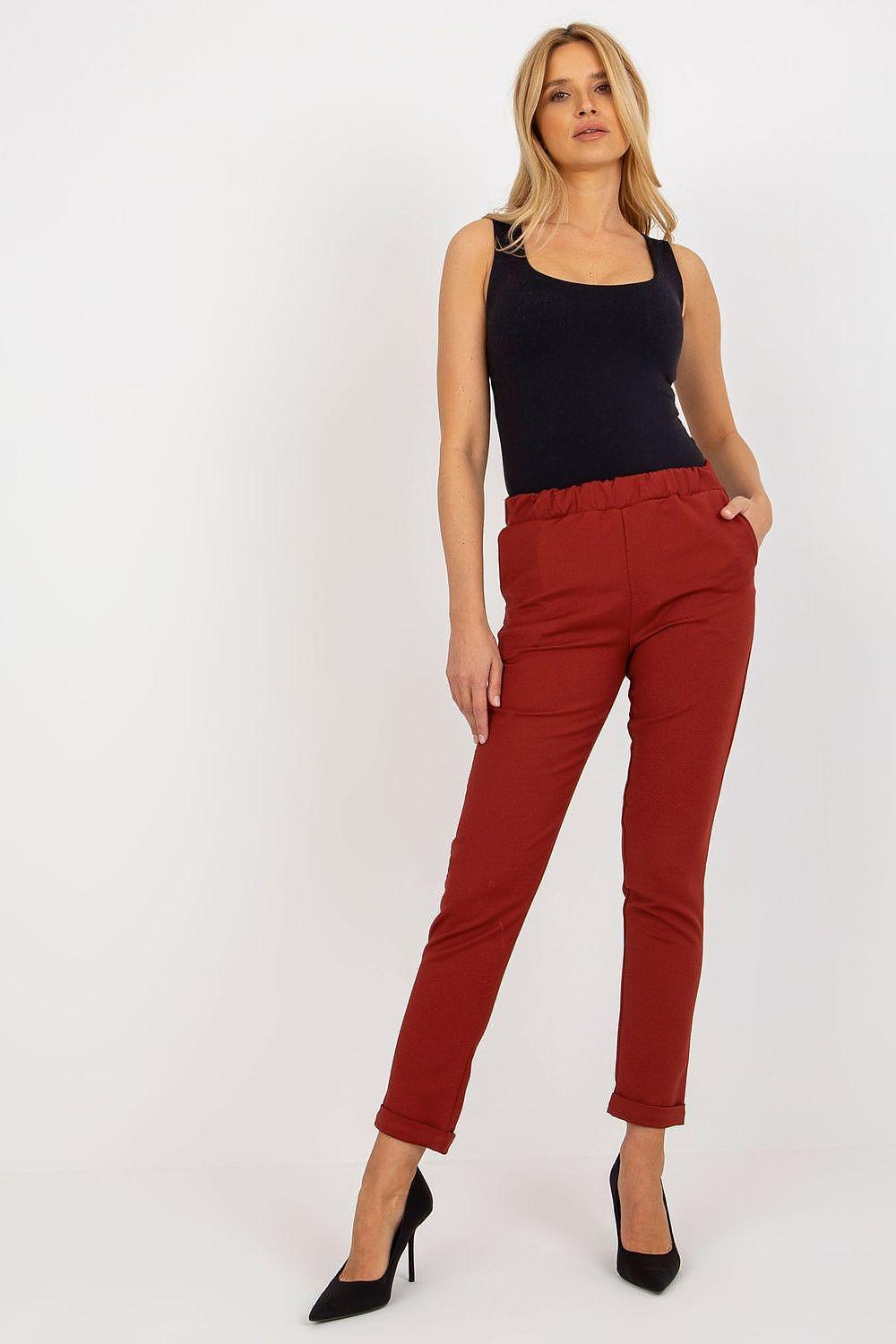Red fitted ankle trousers with front seams and belt loops.