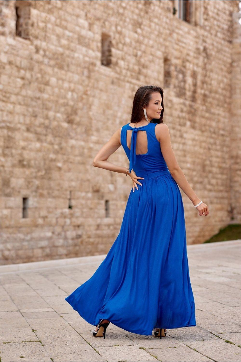 Blue long dress with open back, gathered waist, and flowing skirt with slit.