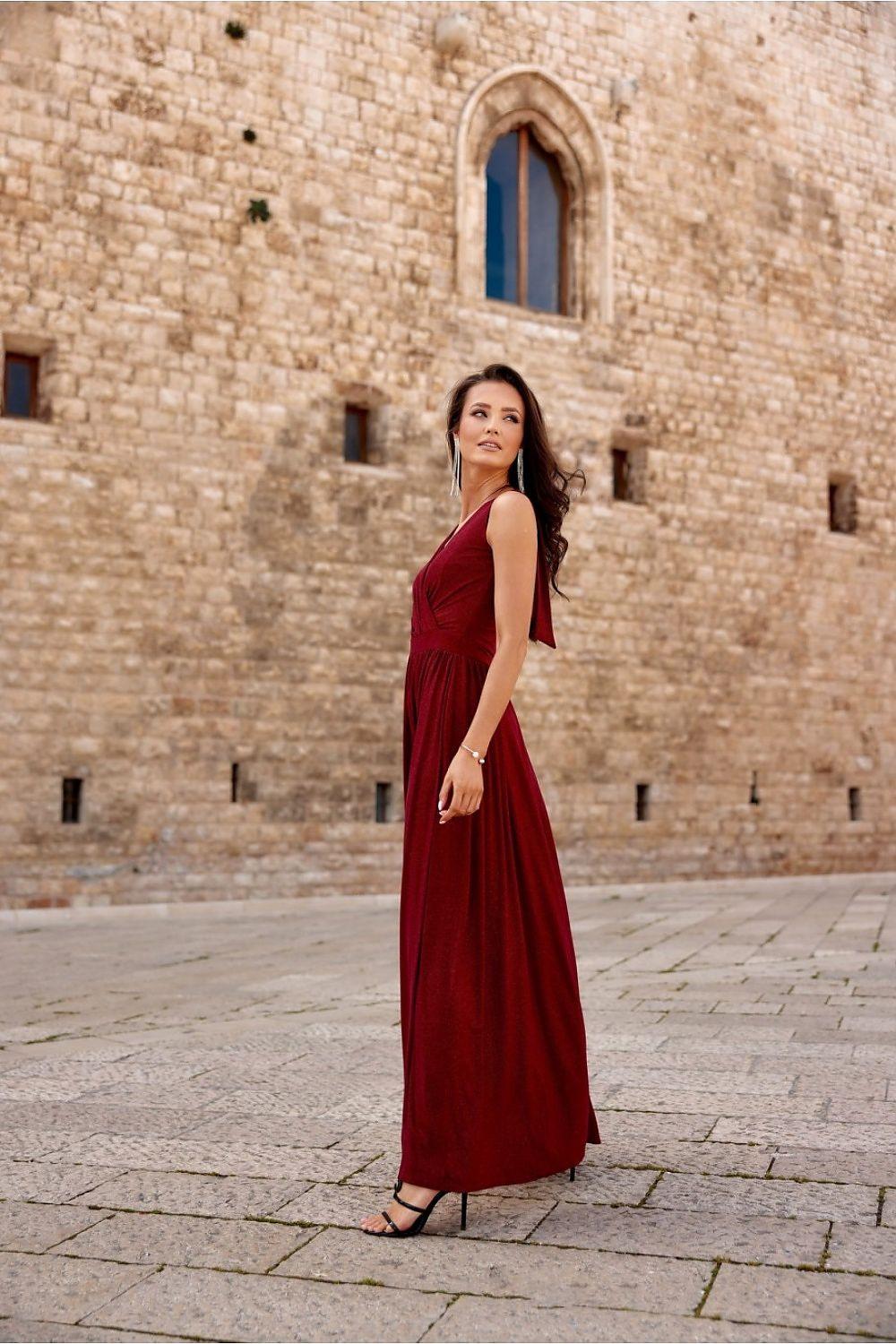 Red long sleeveless dress with V-neck and flowing skirt with side thigh slit.