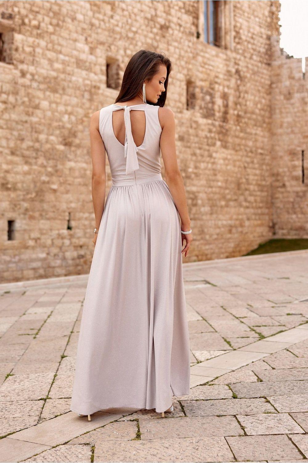 Long sleeveless white dress with open back and gathered waist, with side slit.